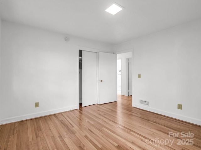 unfurnished bedroom with baseboards, light wood-style flooring, and a closet