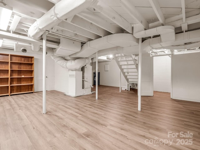 finished below grade area featuring wood finished floors, stairway, and water heater