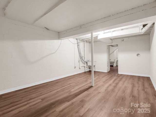 finished below grade area with wood finished floors, baseboards, stairs, and concrete block wall