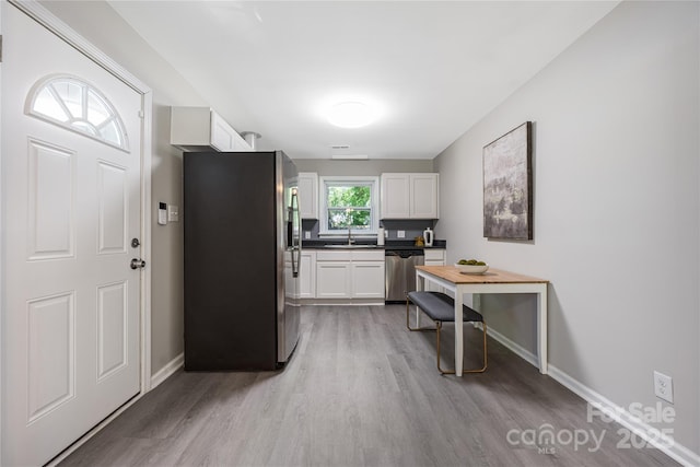 2601 Dora Dr, Charlotte, NC 28215 - kitchen with dark countertops, appliances with stainless steel finishes, light wood finished floors, baseboards, and white cabinetry