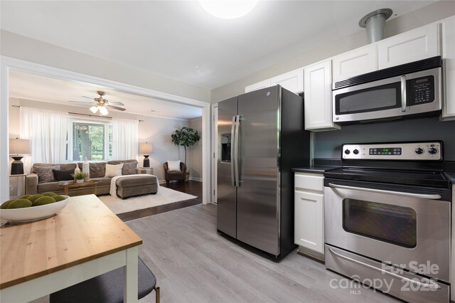 2601 Dora Dr, Charlotte, NC 28215 - kitchen with open floor plan, white cabinetry, stainless steel appliances, and light wood-style flooring