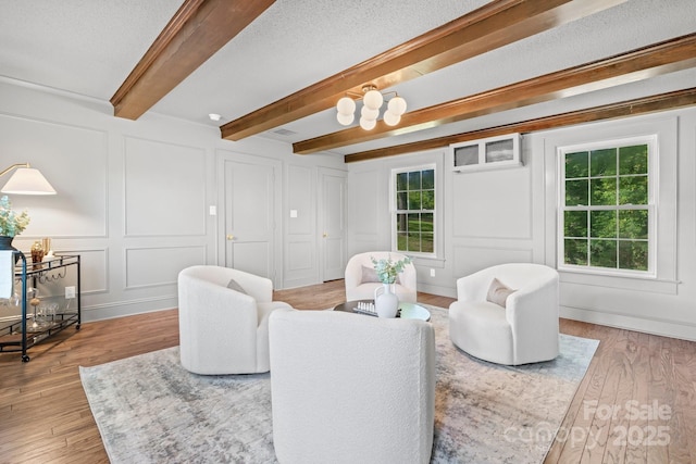625 4th Street Dr NW, Hickory, NC 28601 - living room featuring wood finished floors, a wall unit AC, a decorative wall, and beam ceiling