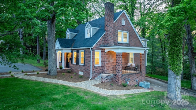625 4th Street Dr NW, Hickory, NC 28601 - tudor home featuring covered porch, a chimney, a front yard, and brick siding