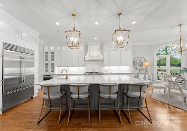13420 Robert Walker Dr, Davidson, NC 28036 - kitchen featuring custom exhaust hood, built in fridge, a sink, a large island with sink, and a chandelier