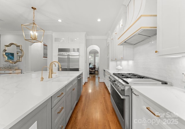 13420 Robert Walker Dr, Davidson, NC 28036 - kitchen featuring arched walkways, a sink, premium appliances, gray cabinetry, and custom range hood