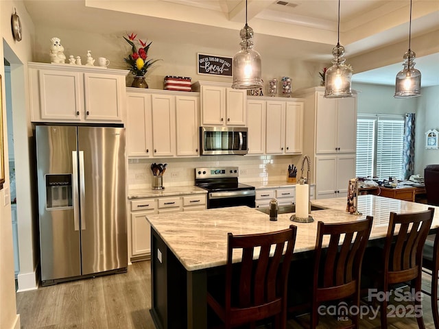 2704 Watergarden St, York, SC 29745 - kitchen featuring appliances with stainless steel finishes, an island with sink, white cabinets, wood finished floors, and backsplash