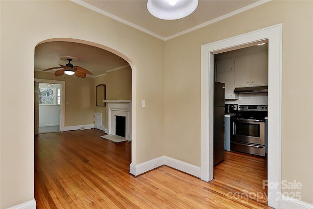 interior space featuring arched walkways, light wood-type flooring, crown molding, and baseboards