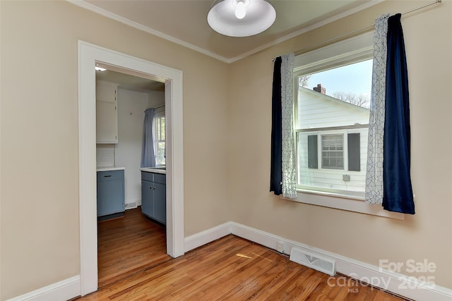 unfurnished room with baseboards, ornamental molding, light wood finished floors, and visible vents