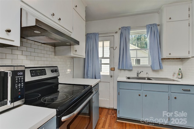 kitchen with electric stove, decorative backsplash, light countertops, light wood-style flooring, and under cabinet range hood