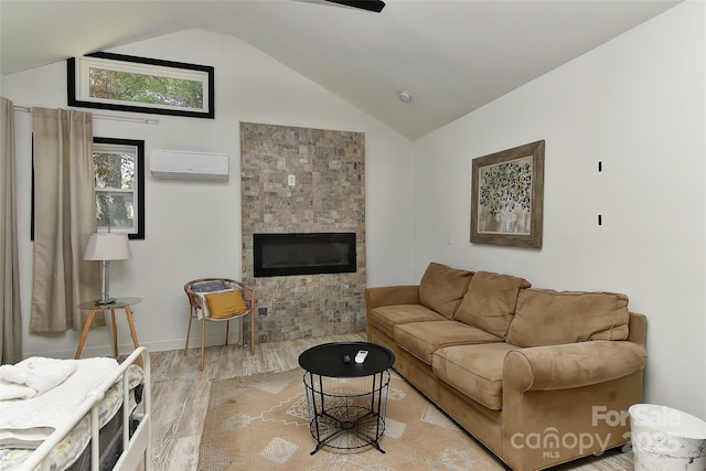 living room featuring lofted ceiling, light wood-style flooring, a glass covered fireplace, and a wall unit AC