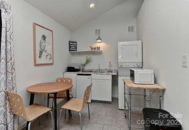 kitchen with stacked washer and clothes dryer, lofted ceiling, visible vents, and light tile patterned floors