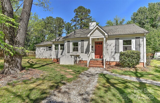 view of front of home with fence, roof with shingles, and a front yard