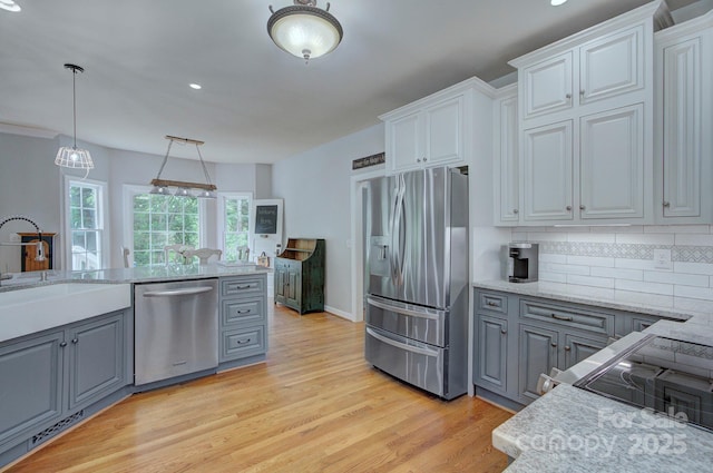 kitchen featuring gray cabinetry, stainless steel appliances, light wood finished floors, and a sink