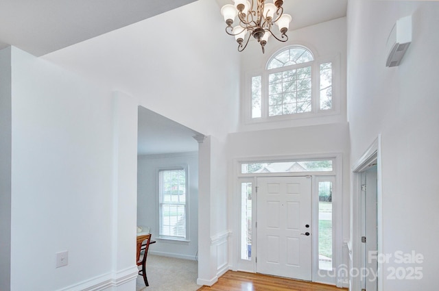 entryway featuring baseboards, a high ceiling, light wood-style flooring, and a notable chandelier