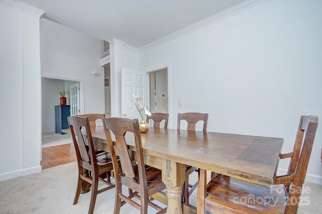 dining area with baseboards, ornamental molding, and light carpet