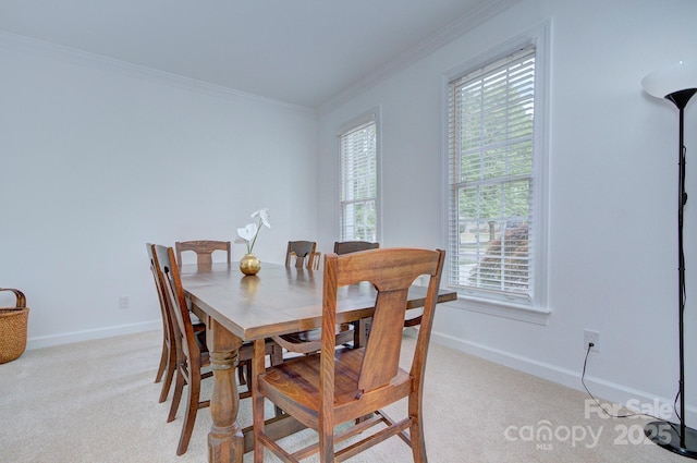 dining room featuring baseboards, ornamental molding, and light carpet