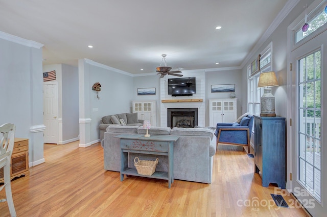 living area with light wood-type flooring, a ceiling fan, a brick fireplace, and recessed lighting