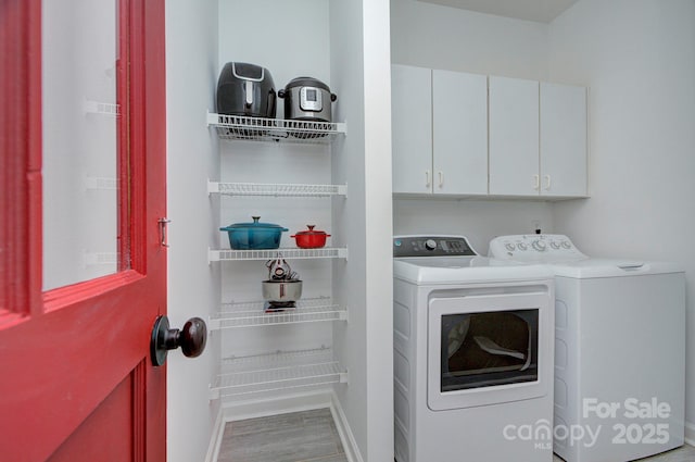 clothes washing area with baseboards, cabinet space, independent washer and dryer, and wood finished floors