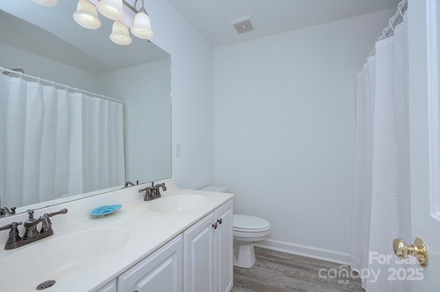 full bath with a sink, toilet, wood finished floors, and visible vents