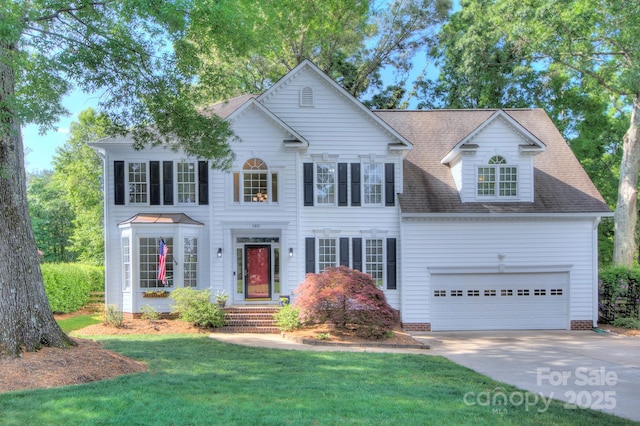 colonial inspired home with driveway, a front lawn, roof with shingles, and a garage