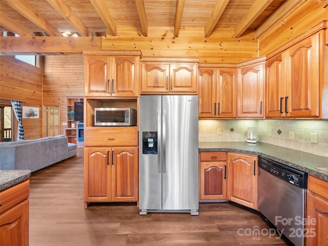 kitchen with dark countertops, wood ceiling, beamed ceiling, stainless steel appliances, and wood walls