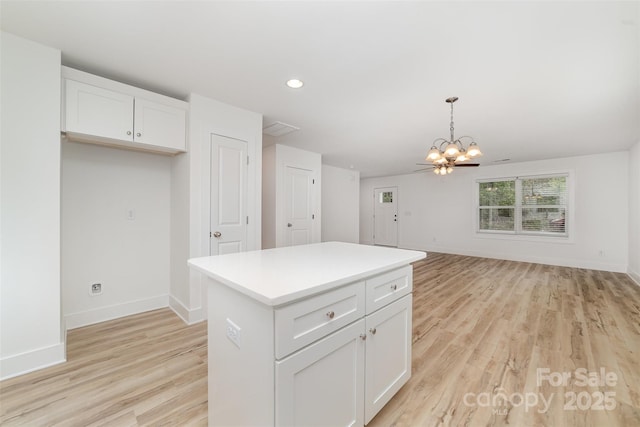 kitchen featuring baseboards, a chandelier, light wood-style flooring, white cabinets, and decorative light fixtures