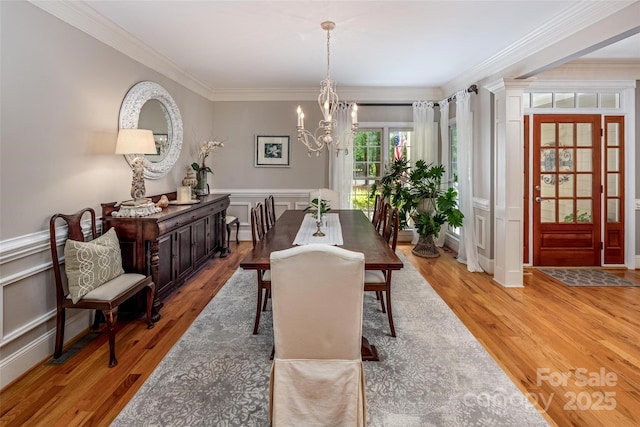 19729 Callaway Hills Ln, Davidson, NC 28036 - dining room with light wood-style flooring, a wainscoted wall, crown molding, an inviting chandelier, and a decorative wall