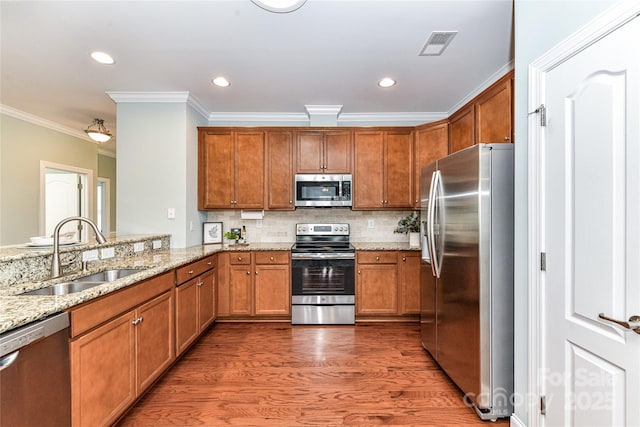 11123 Bailey Park Nature Dr, Cornelius, NC 28031 - kitchen with a sink, brown cabinets, stainless steel appliances, ornamental molding, and light stone countertops