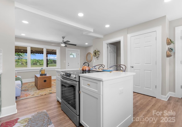 155 Jackson Rd, Salisbury, NC 28146 - kitchen with a kitchen island, stainless steel electric range, white cabinetry, light countertops, and light wood-style flooring