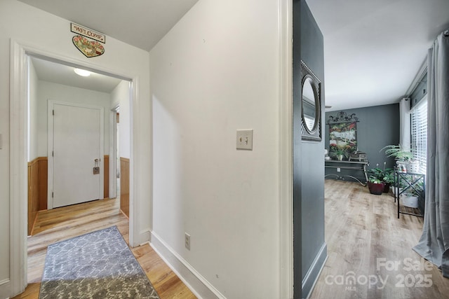 corridor featuring baseboards and light wood finished floors