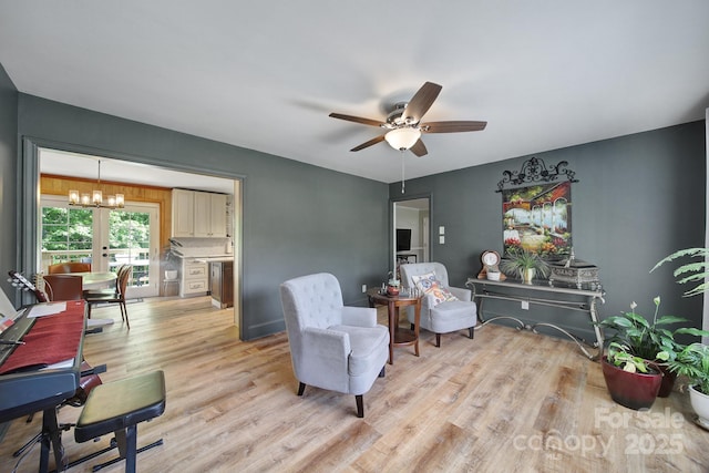 living area featuring light wood-style flooring and ceiling fan with notable chandelier