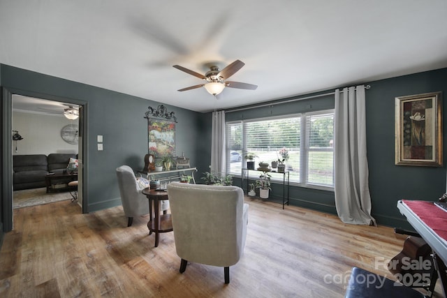 living area featuring baseboards, ceiling fan, and wood finished floors