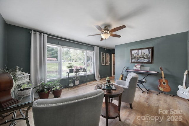 living room with baseboards, a ceiling fan, and wood finished floors