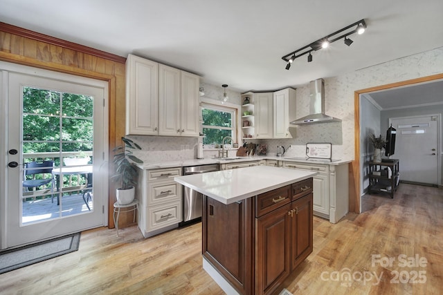 kitchen featuring wall chimney range hood, light countertops, decorative backsplash, and dishwasher