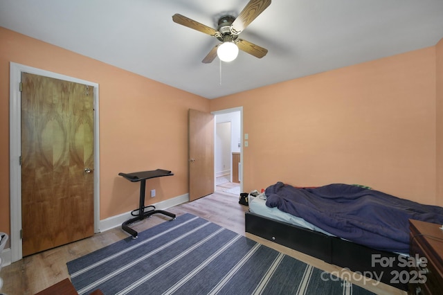 bedroom with a ceiling fan, baseboards, and wood finished floors
