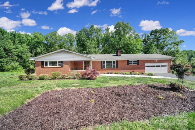 single story home featuring brick siding, a chimney, a front lawn, and a garage