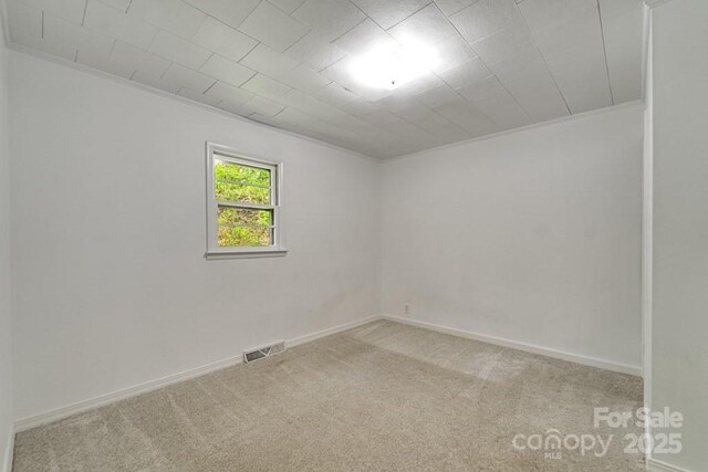 unfurnished room featuring carpet floors, baseboards, visible vents, and ornamental molding