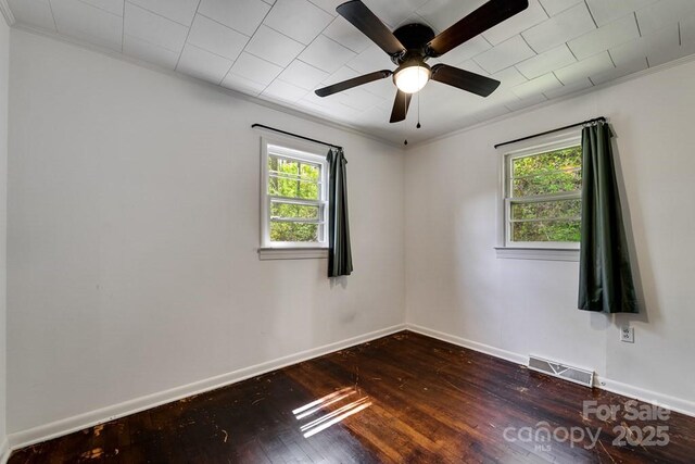 spare room with baseboards, ornamental molding, dark wood-type flooring, and visible vents