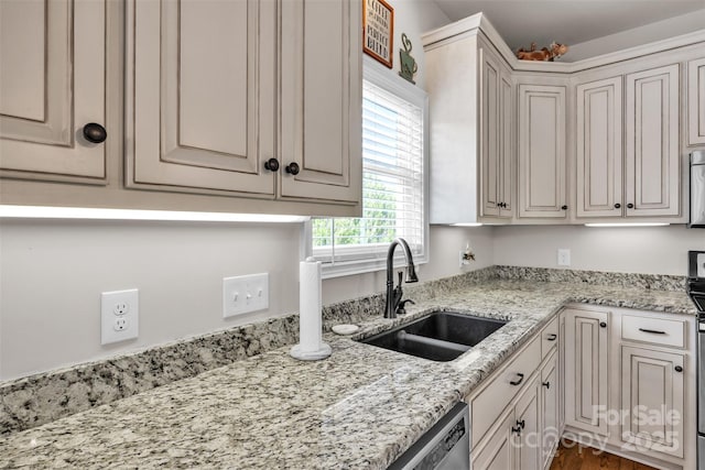 kitchen featuring wood finished floors, stainless steel microwave, light stone countertops, and a sink