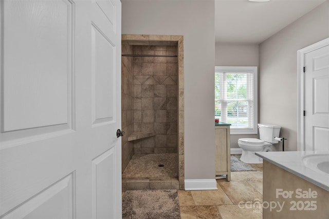 bathroom featuring baseboards, vanity, a walk in shower, and toilet