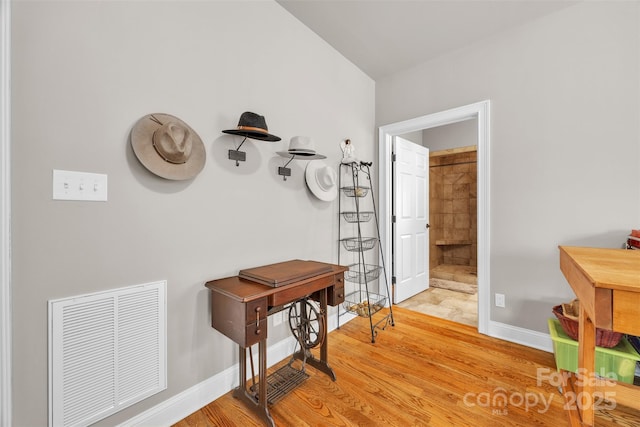 hallway featuring light wood-style floors, visible vents, and baseboards