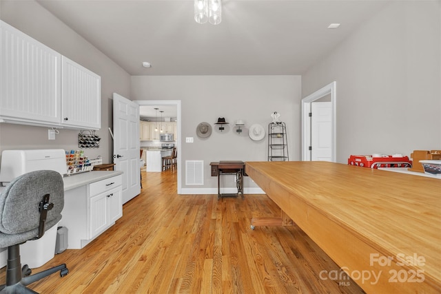 interior space featuring light wood-type flooring, visible vents, and baseboards