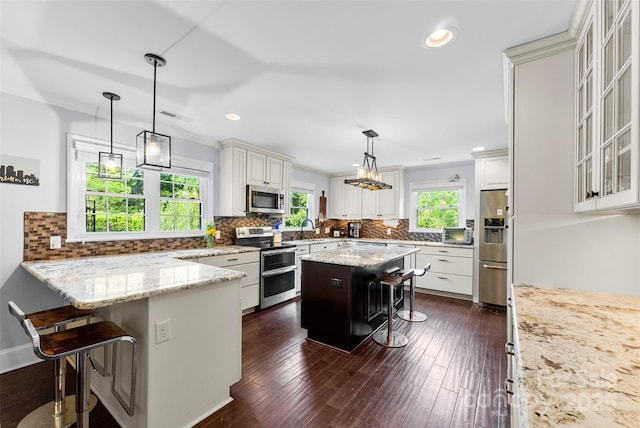 kitchen featuring a breakfast bar area, stainless steel appliances, visible vents, and light stone counters