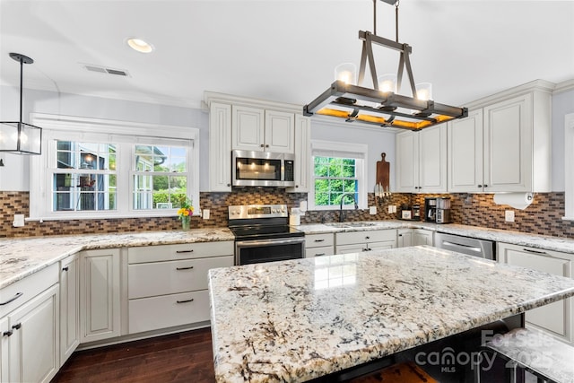 kitchen featuring light stone countertops, dark wood-type flooring, a sink, backsplash, and stainless steel appliances