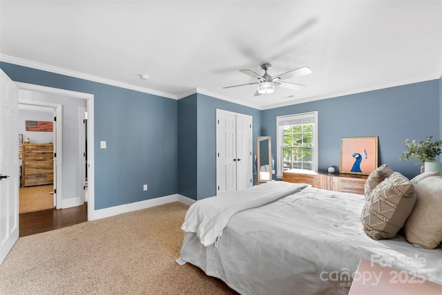 carpeted bedroom with baseboards, ornamental molding, ceiling fan, and a closet
