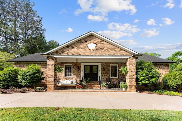view of front facade with brick siding, french doors, and covered porch