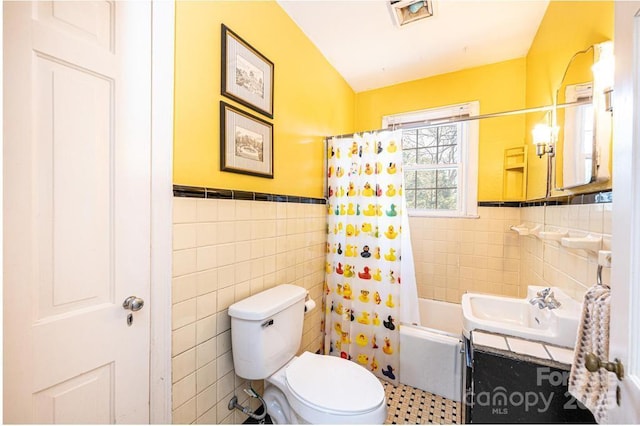 310 1st St NE, Hickory, NC 28601 - bathroom with vanity, tile walls, a wainscoted wall, toilet, and shower / bath combo with shower curtain