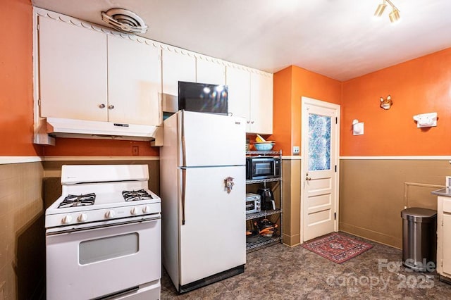310 1st St NE, Hickory, NC 28601 - kitchen featuring white cabinets, a wainscoted wall, tile walls, white appliances, and under cabinet range hood