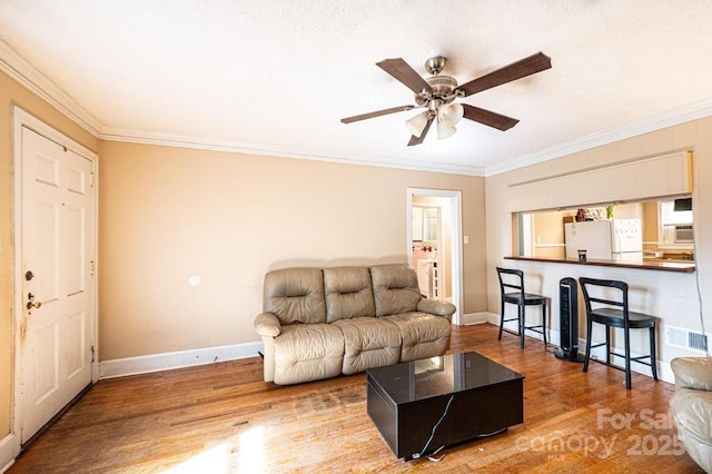310 1st St NE, Hickory, NC 28601 - living room featuring visible vents, baseboards, a ceiling fan, wood finished floors, and crown molding