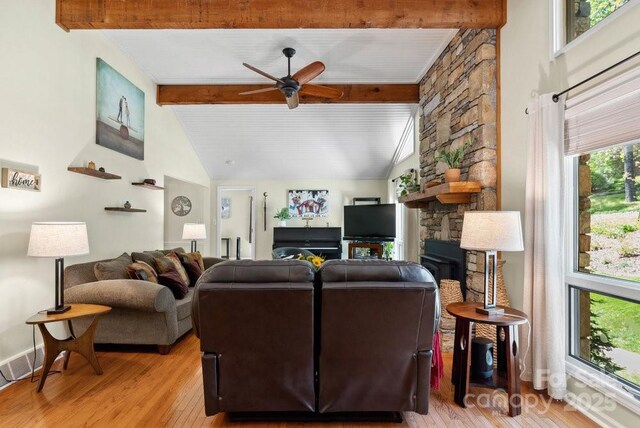 living area with a fireplace, ceiling fan, lofted ceiling with beams, and light wood-type flooring